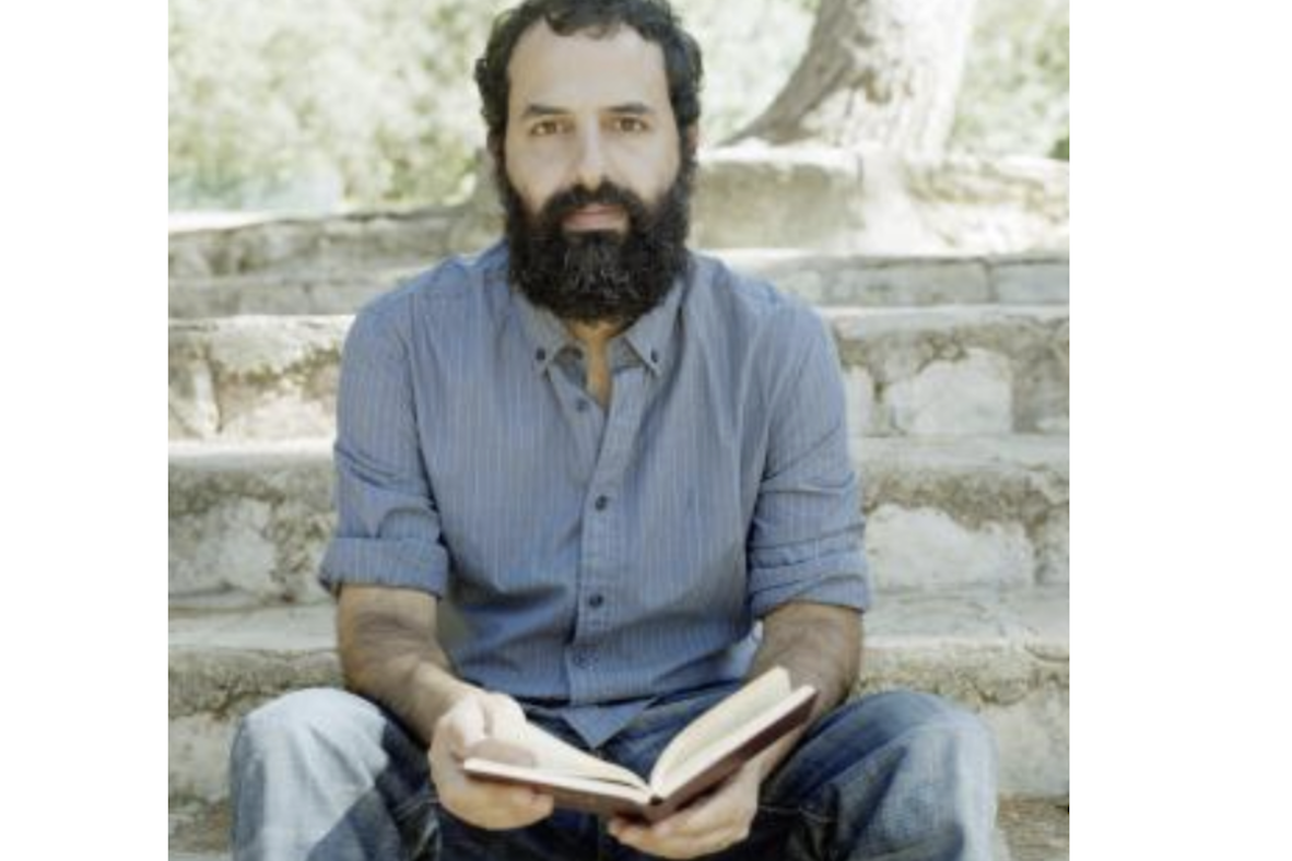 man holding book open and looking at camera taking picture